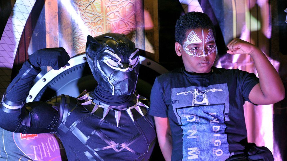 A fan poses with a cosplayer portraying a character from the 2018 US superhero film based on the Marvel Comics character, 'The Black Panther' pose in the Kenyan capital, Nairobi on February 14, 2018