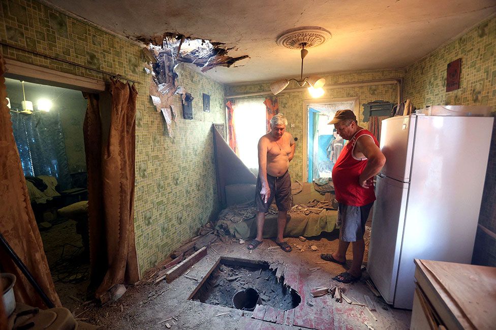 Local residents look at the damage to a building partially destroyed overnight during a missile strike on the outskirts of Kramatorsk, Donetsk region, Ukraine, on 25 July 2022