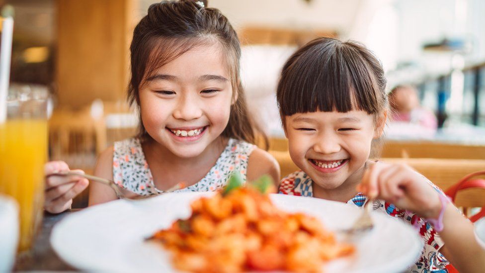 two girls smiling looking at pasta