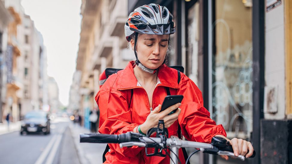 Stock image of a woman on a bike using a mobile phone