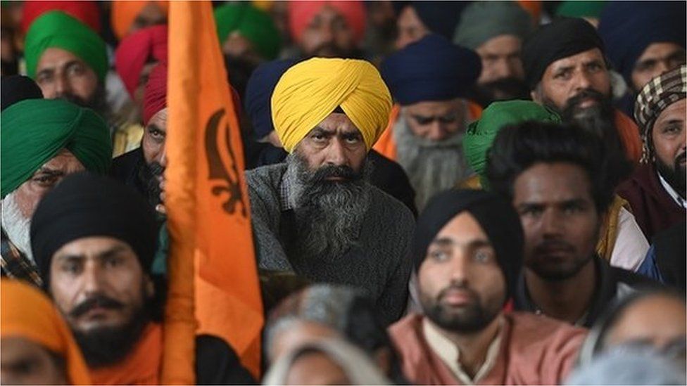 Farmers listen to a speaker during a protest against the central government's recent agricultural reforms, at the Delhi-Haryana state border in Singhu on January 27, 202