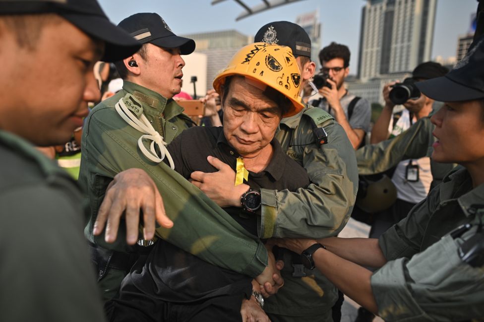 Một người đàn ông được cảnh sát hộ tống khi ông tìm cách nhảy xuống biển ở quận Tsim Sha Tsui, Hong Kong hôm 1/10 năm 2019 giữa lúc các cuộc biểu tình dữ dội dự kiến xảy ra khắp thành phố
