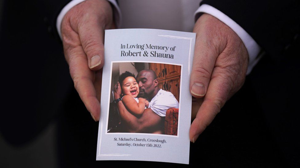 A person holding a funeral service booklet displaying an image of Shauna and Robert