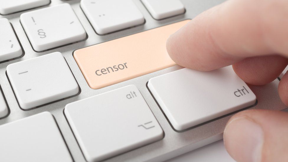 A stock photo showing a finger hovering above a computer keyboard with a button marked 'censor'