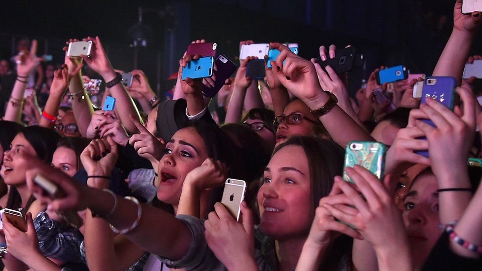 A concert with people holding smartphones aloft