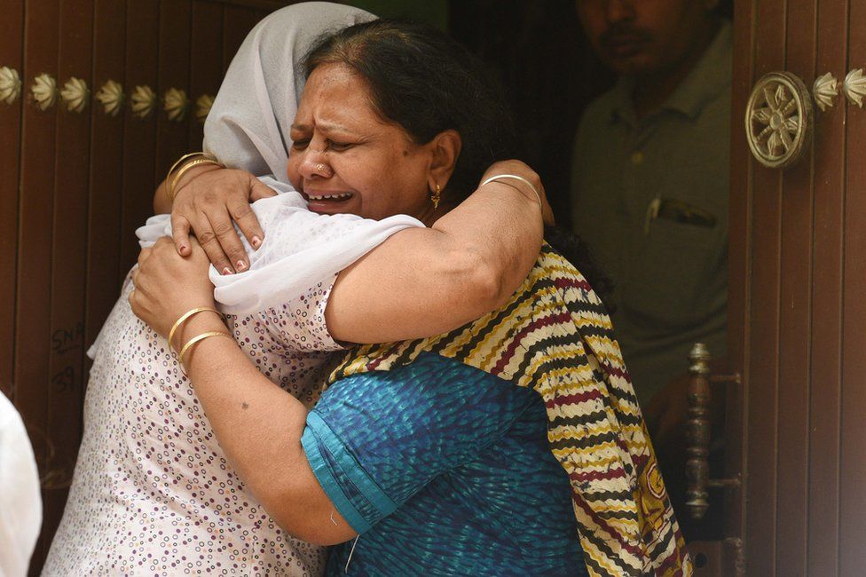 Relatives mourn outside the house, where 11 members of a family were found dead in Delhi.