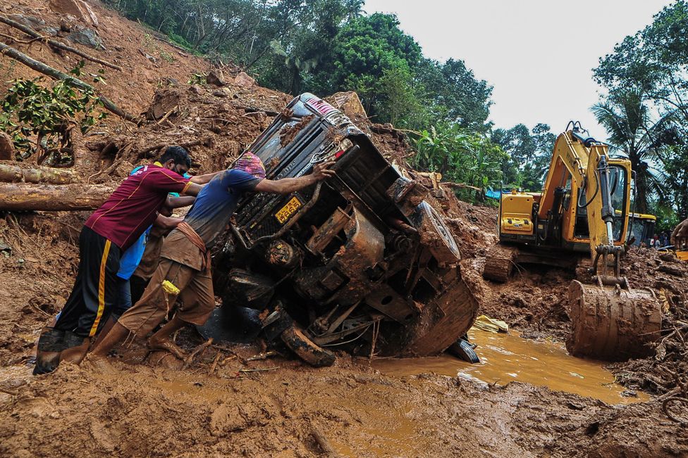 Rescue workers push an overturned vehicle stuck in the mud and debris at the site of a landslide apparently caused by heavy rains in Kokkayar, Kerala state, India, on 17 October 2021