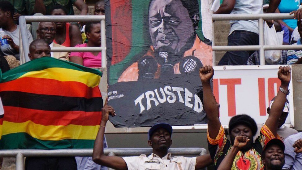 Supporters hold a portrait of Zimbabwe's new President Emmerson Mnangagwa on 24 Nov