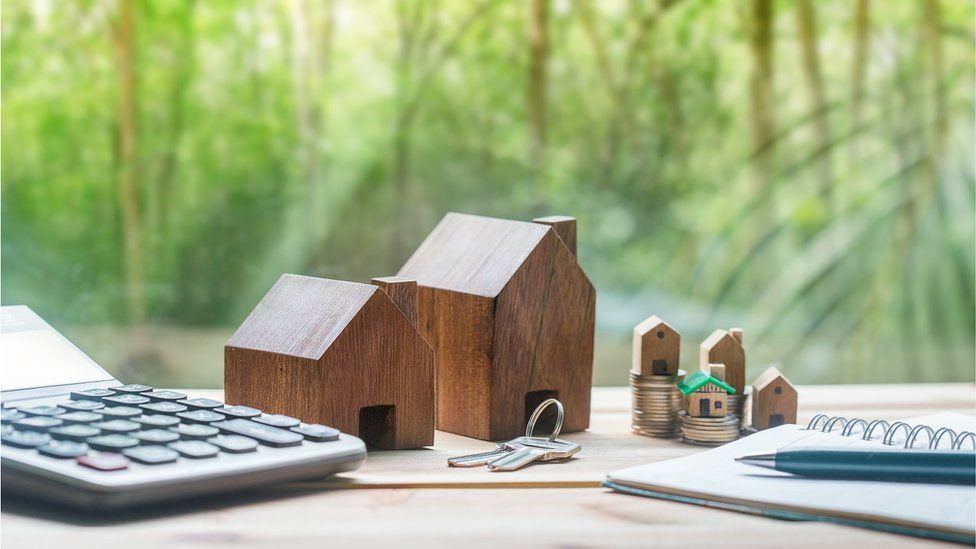 Model houses placed next to coins on a desk