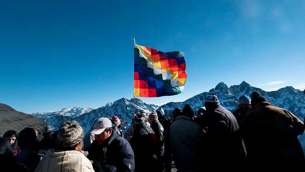 A group with the Wiphala, the co-official flag of Bolivia since 2009, with its multicoloured squares representing the native peoples of all the Andes