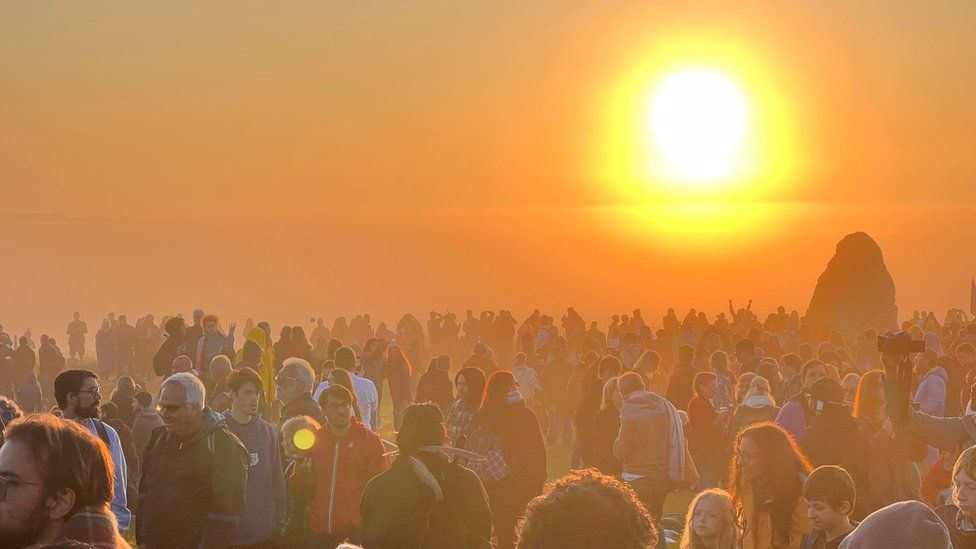 Crowds watching the sun rise - the sun is glowing brightly