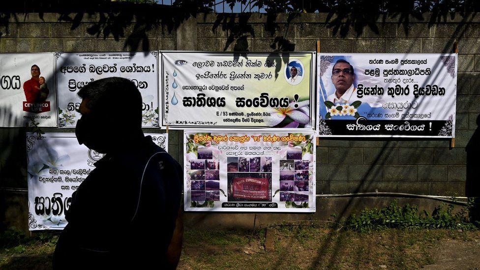 A man walks past funeral banners of Sri Lanka's factory manager Priyantha Diyawadanage in Ganemulla, about 33 km from Colombo on December 7, 2021
