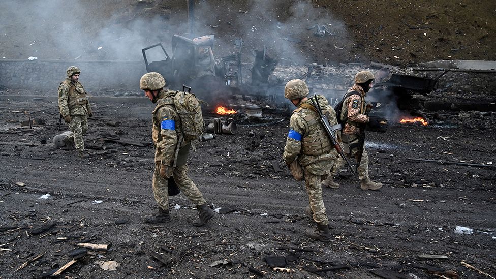 Ukrainian service members are seen at the site of a fighting with Russian raiding group in the Ukrainian capital of Kyiv in the morning of February 26, 2022