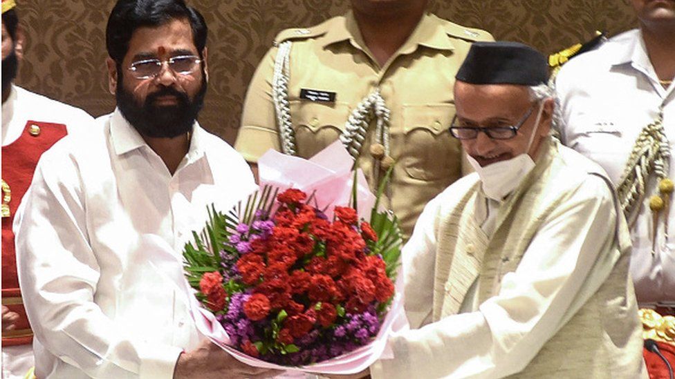 Shiv Sena party leader and new Chief Minister of Maharashtra state Eknath Shinde (L) receives a flower bouquet from the Governor of Maharashtra Bhagat Singh Koshiyari after taking the oath, in Mumbai on June 30, 2022. (