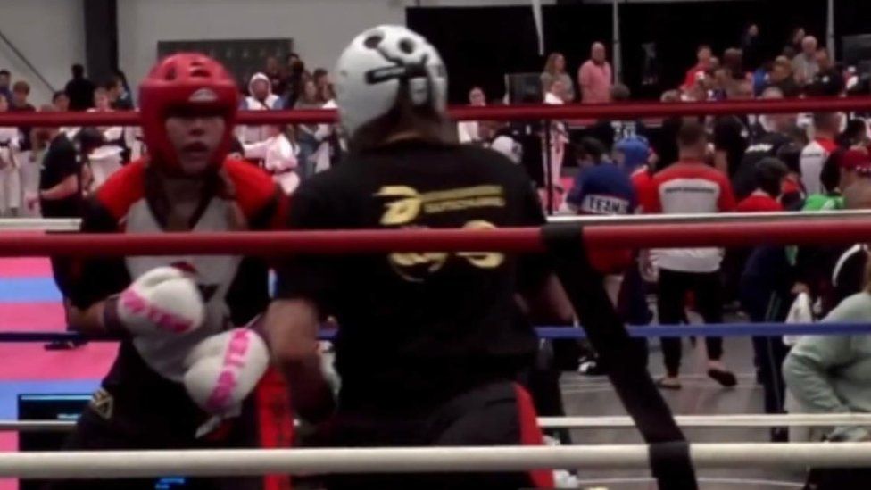 Two female competitors with helmets in a boxing ring