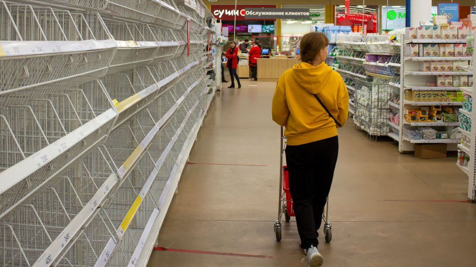 A woman walks by empty shelves in a supermarket in Moscow. There has been shortages of women's sanitary pads, diapers, and sugar