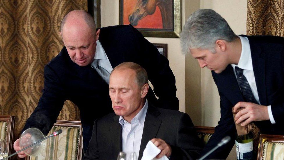 Yevgeniy Prigozhin (L) assists Russian Prime Minister Vladimir Putin during a dinner with foreign scholars and journalists at the restaurant Cheval Blanc on the premises of an equestrian complex outside Moscow November 11, 2011