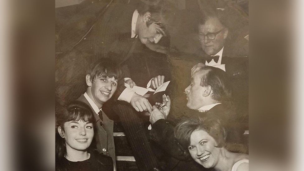 John Lennon (top left) signing an autograph with Ringo Starr (left of middle row)