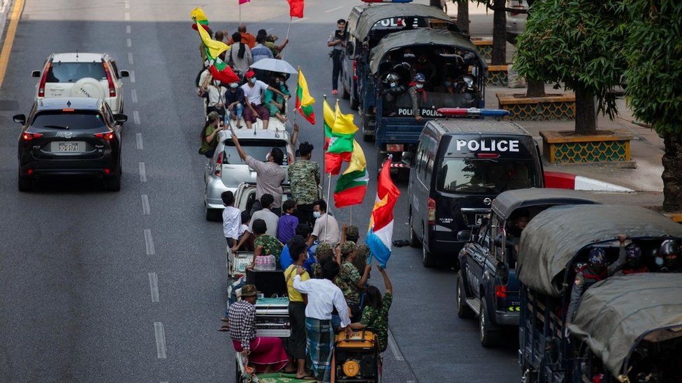 Сторонники военных подъезжают к полицейским грузовикам, припаркованным у улиц Янгона.