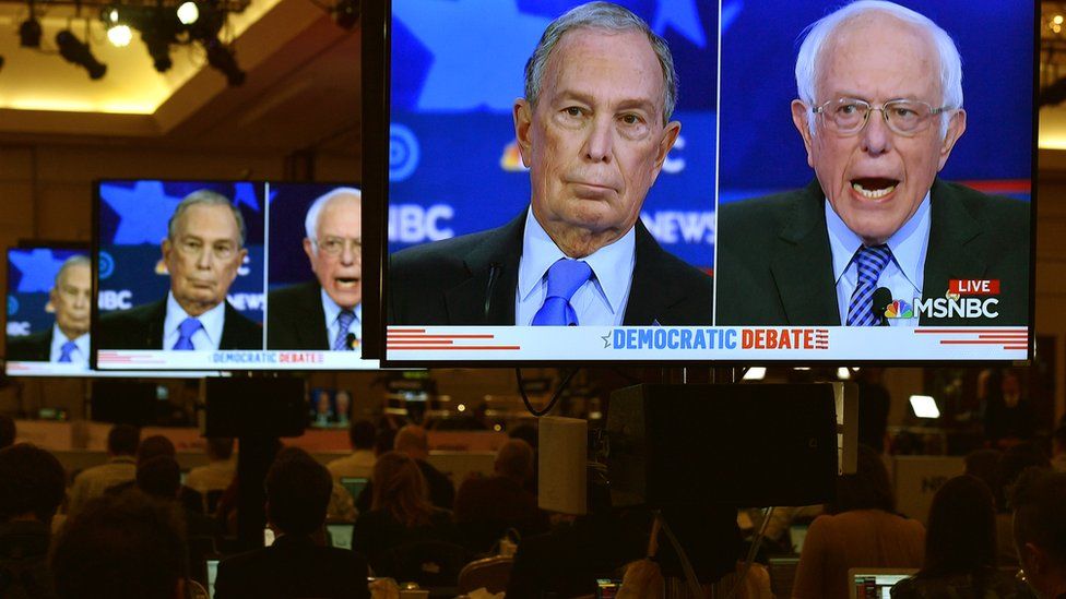 TV screens showing Bloomberg and Sanders
