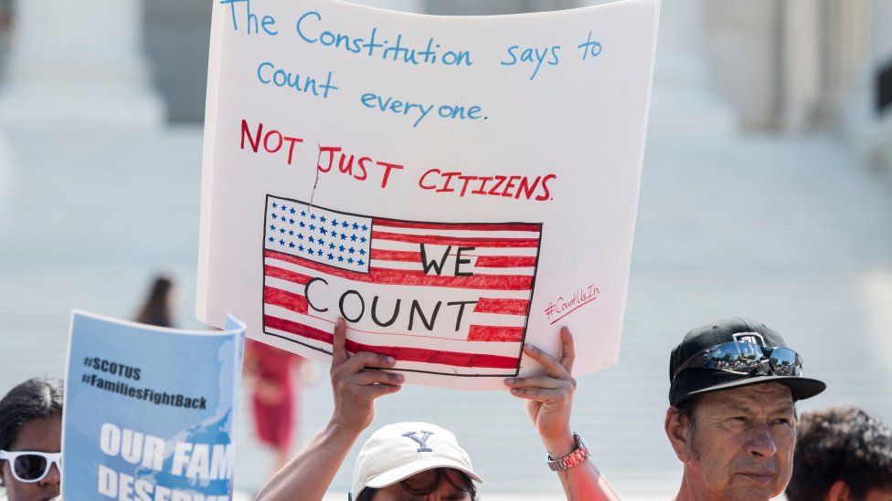 A protester calls for non-citizens to be counted