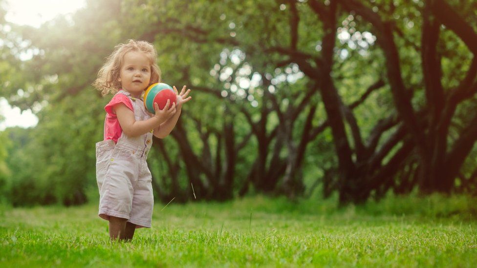 Small girl with ball in field