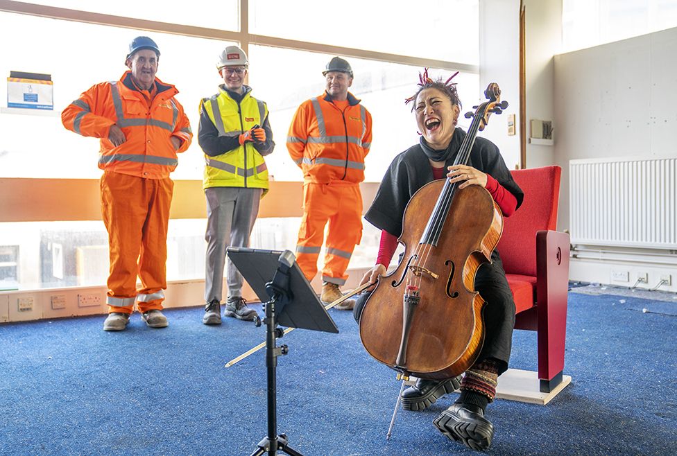 Scottish Chamber Orchestra's principal cellist, Su-a Lee, plays to an audience of construction workers marking the first day of work ahead of building the Dunard Centre concert hall. Edinburgh. 6 February 2023.