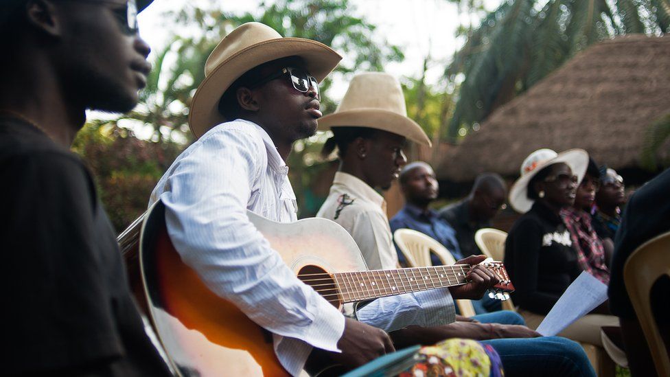 Churchill Olum playing a guitar in Kampala