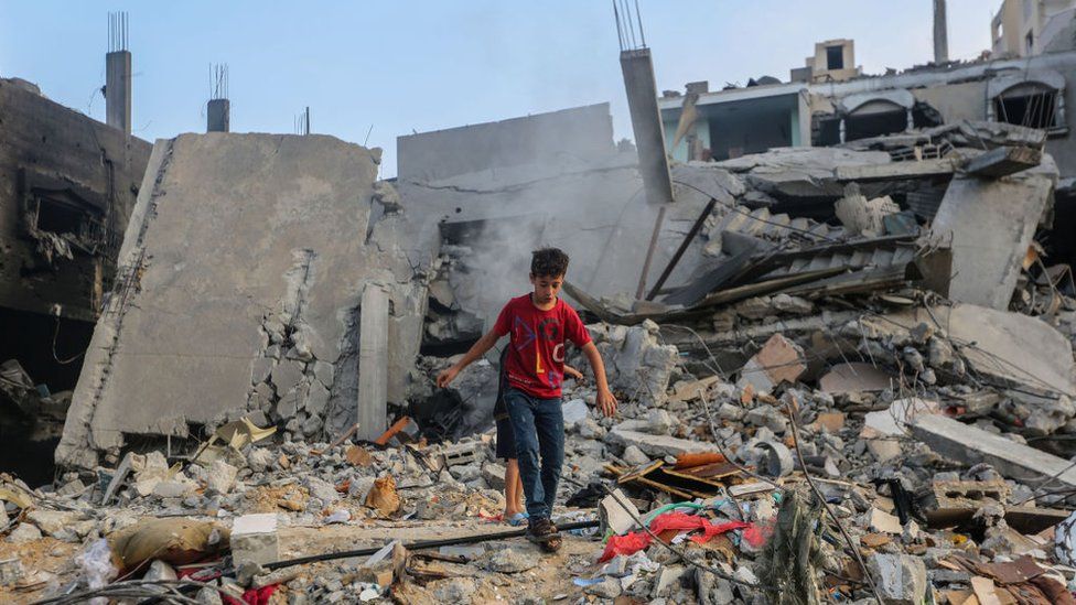 Children search through buildings, destroyed during Israeli air raids in Khan Yunis in the southern Gaza Strip on 8 November, 2023