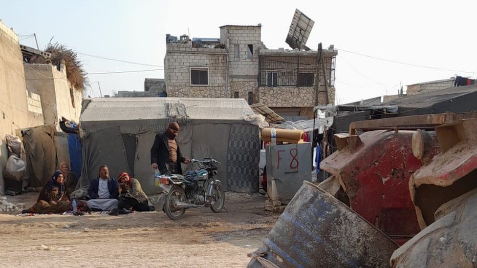 La familia del bebé Adnan sentada junto a una tienda de campaña después de que su casa en Jindayris, Siria, fuera destruida por un terremoto