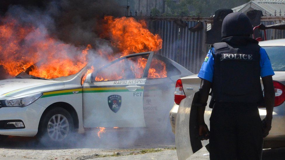 Policeman in front of burning vehicle