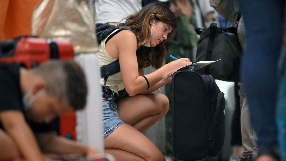 Пассажир заполняет форму в очереди на регистрацию Ryanair в Испании