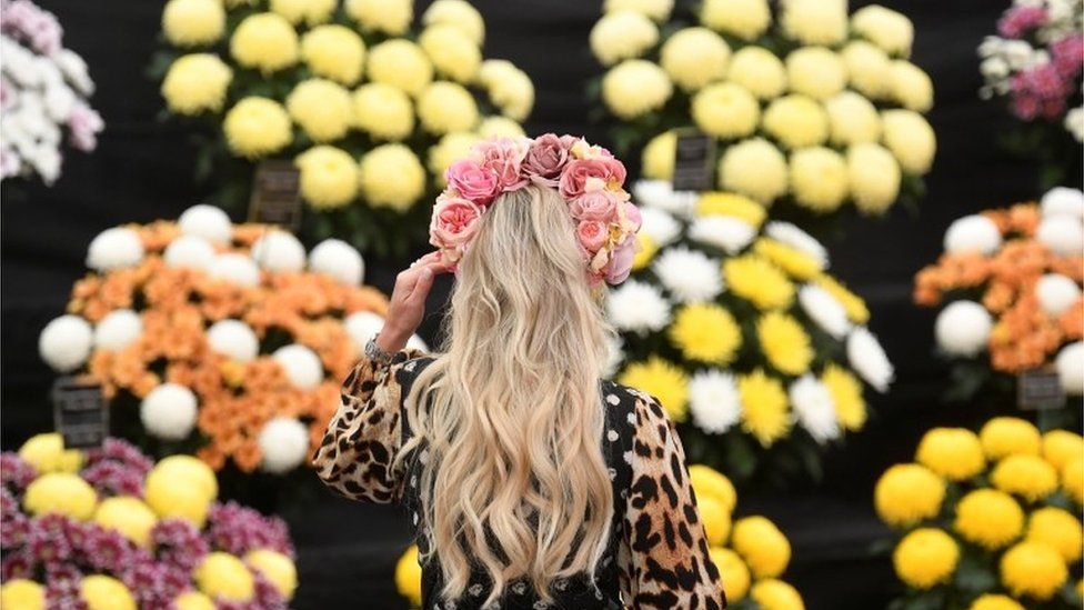 A woman wearing a flower headband attends the RHS Chelsea Flower Show,
