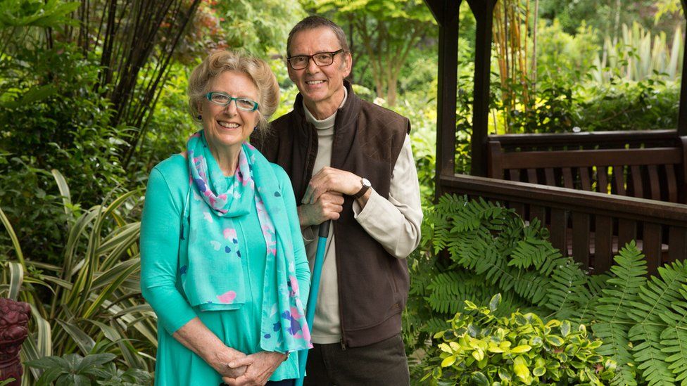 Marie and Tony Newton stood in their garden with lots of greenery surrounding them