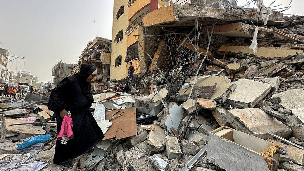 A Palestinian woman searches for her belongings after her apartment was destroyed in an Israeli raid, amid the ongoing conflict between Israel and the Palestinian Islamist group Hamas, in Nuseirat, in the central Gaza Strip, April 18, 2024.