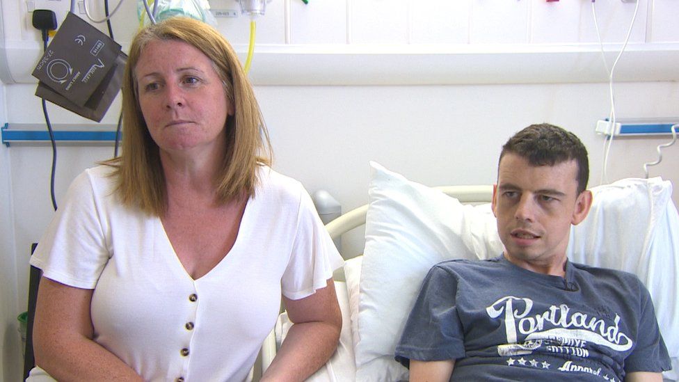 Karen sitting by her son Dean's bedside in hospital
