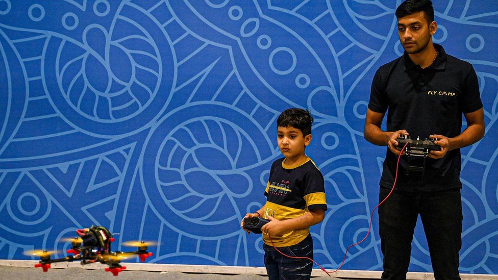 A boy learns to fly a drone under the supervision of a professional drone operator at the "Bharat Drone Mahotsav 2022" drone show in New Delhi on May 27, 2022.