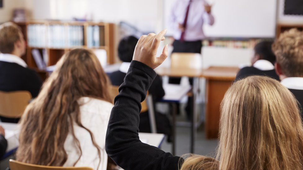 Girl putting her hand up to ask a question in school