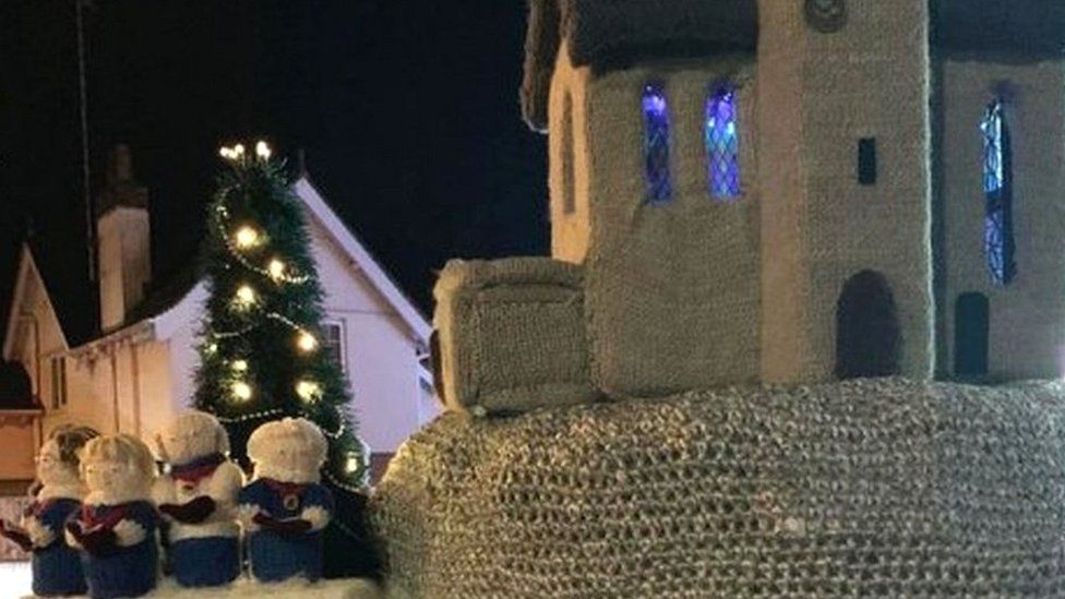 A knitted church and carol singers on top of a postbox