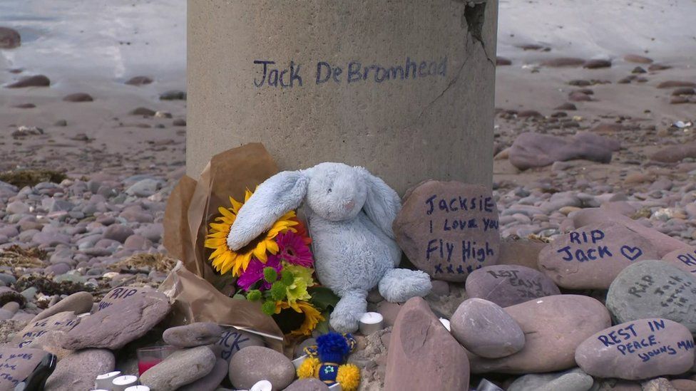 Дань памяти Джеку де Бромхеду, написанная на камнях, оставленных рядом с местом аварии на пляже Россбей