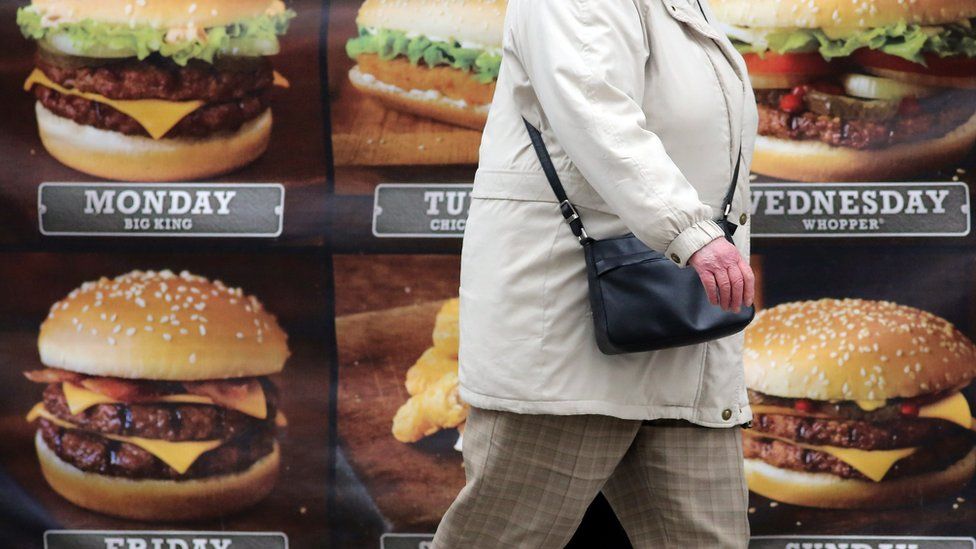 A person walking past an advert for hamburgers