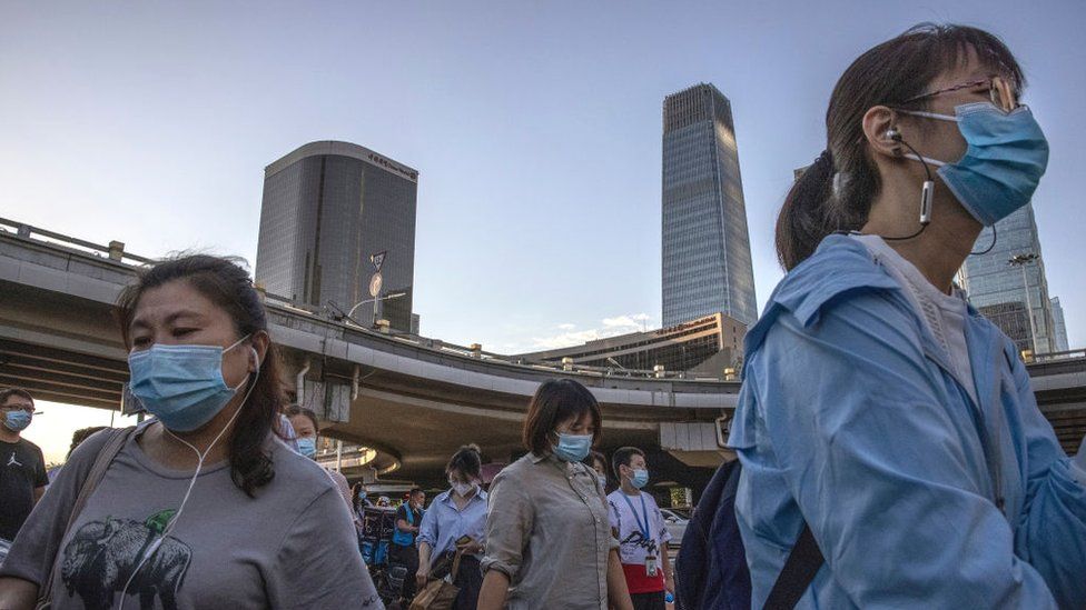 Commuters cross an intersection as they leave work in the business district on August 27, 2021 in Beijing, China