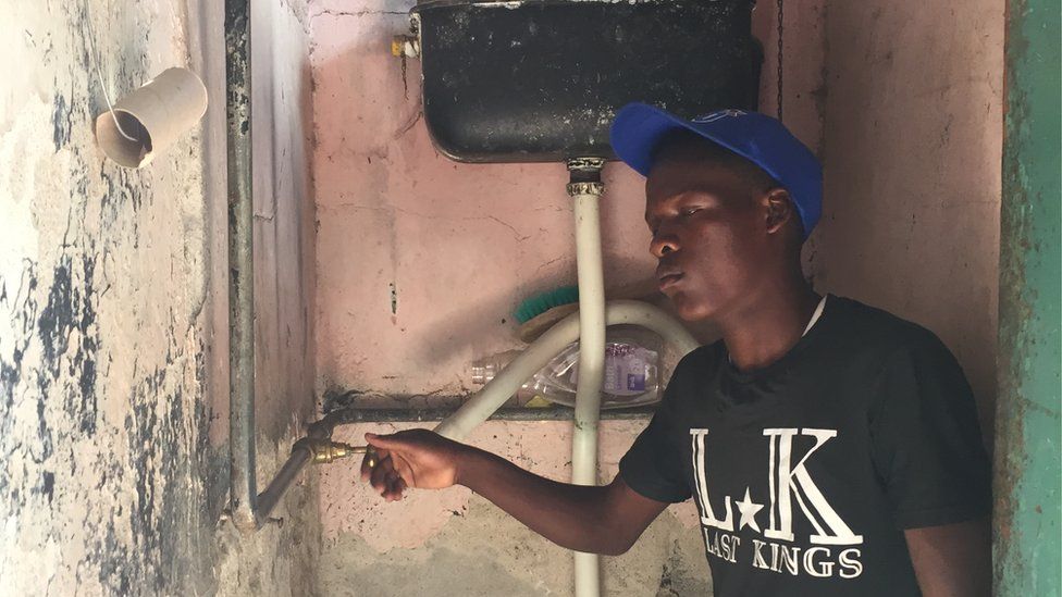 A man turning on the tap in Zimbabwe.