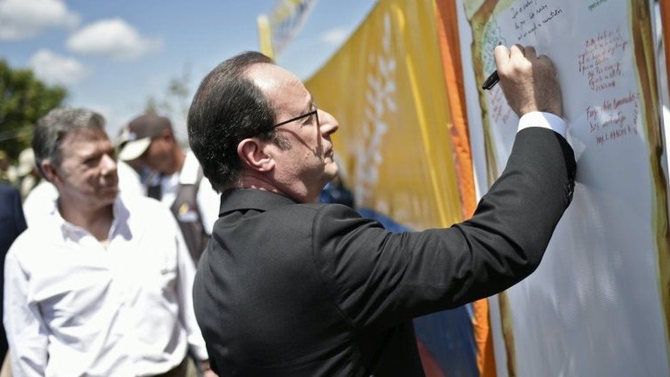 French President Francois Hollande (R) writes a message during a visit to a FARC rebel disarmament zone next to Colombian President Juan Manuel Santos in Caldono, Valle del cauca department, Colombia on January 24, 2017