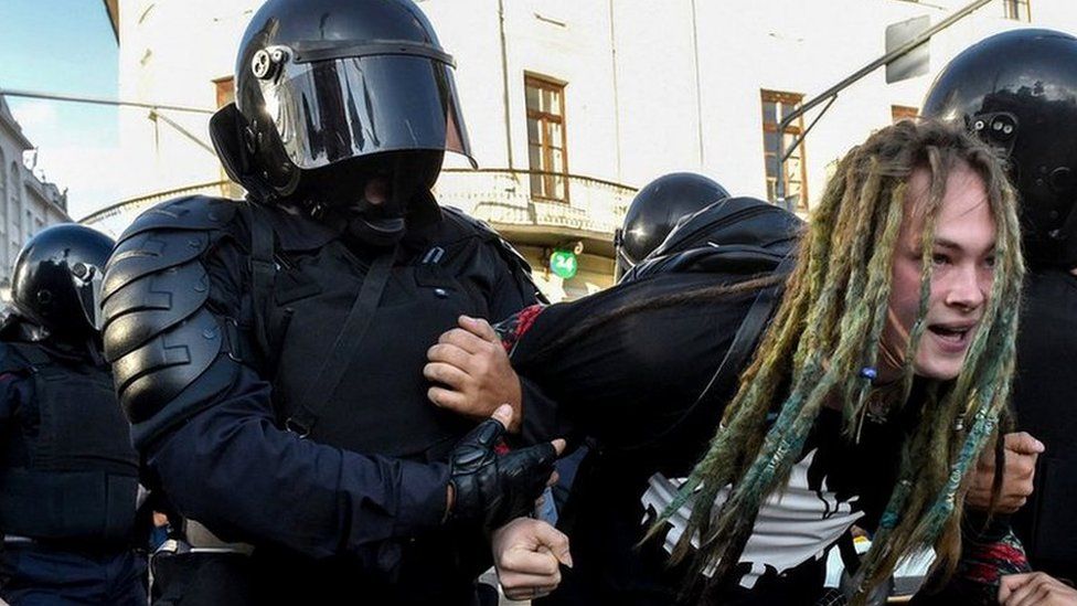 A protester is detained by Russian police on 10 August