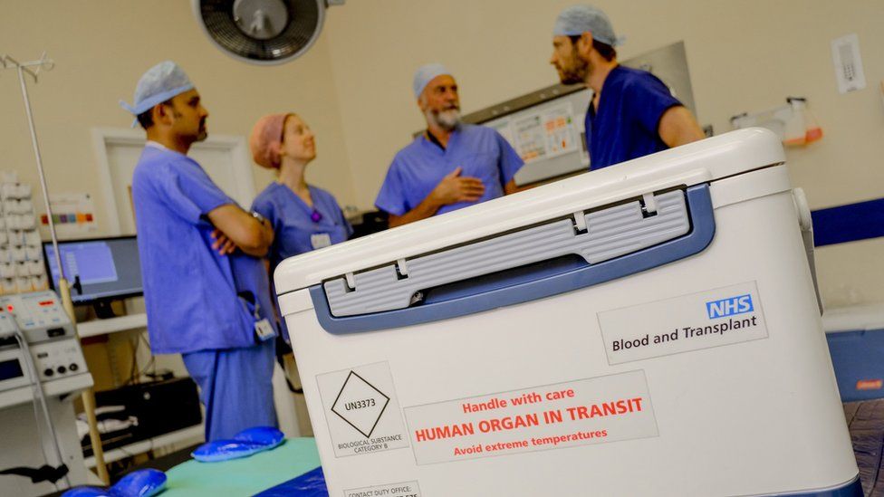An organ in transit in a hospital room filled with doctors