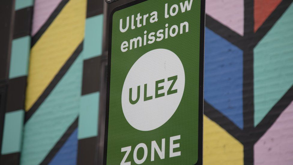 An ultra low emission zone sign in London, against a mural wall's bright colours