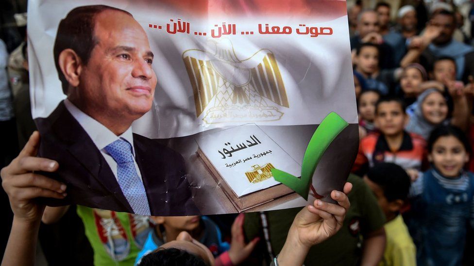 An Egyptian man holds up a banner saying: "Vote with us... now... now" at a polling station in Menoufia (22 April 2019)