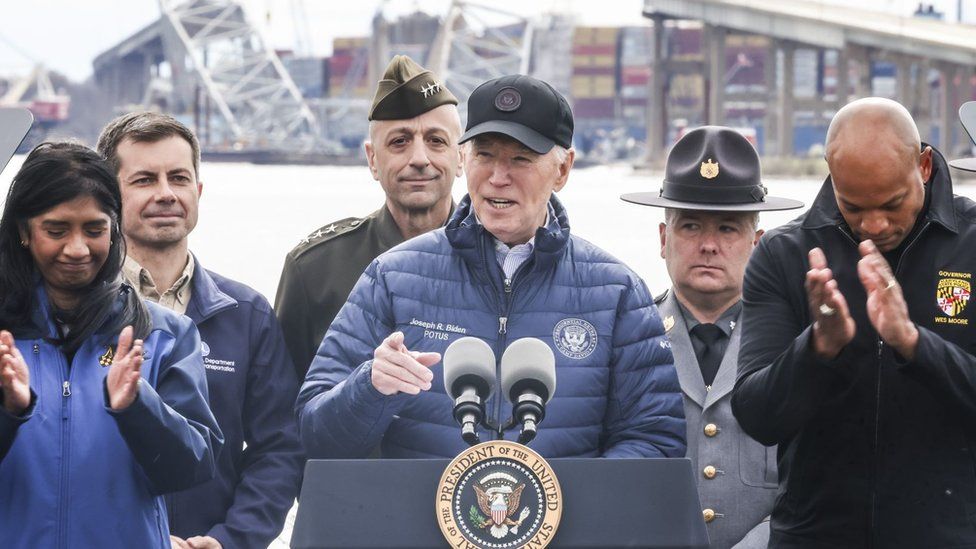 Biden in blue jacket, black cap