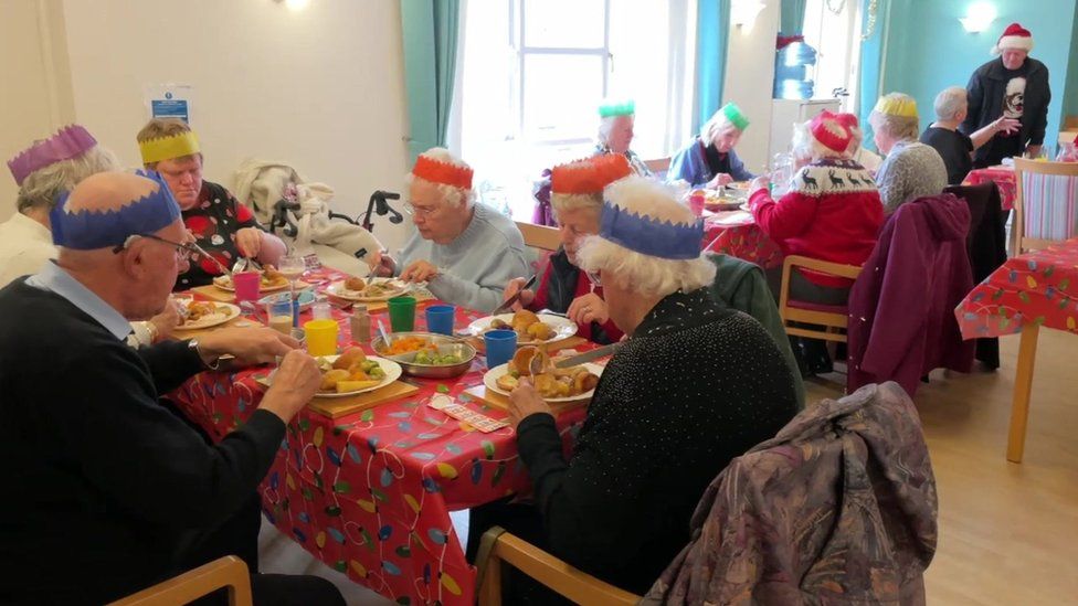 Older people eating Christmas dinner around a table at a community centre in Portland